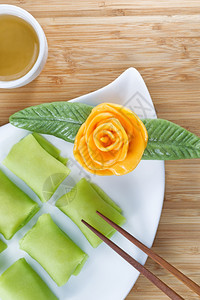 近视的田里水果甜点大米蛋糕黄装饰玫瑰和天然竹底绿茶的垂直形象图片