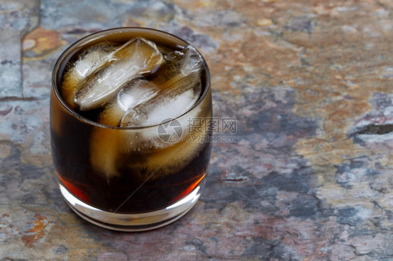 紧贴着新鲜的可乐饮料上面有天然生锈的石板背景上真冰焦点放在玻璃前唇上图片