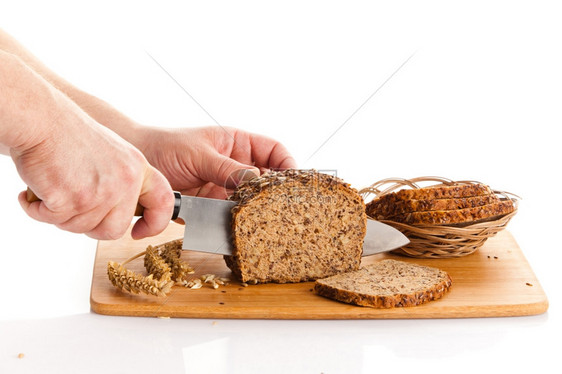 新鲜面包在切肉板上布兰面包手在木板上切面包图片