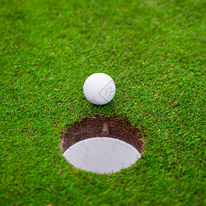 高尔夫球在绿色草地上高尔夫球在杯嘴唇上图片