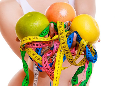 健康保生活方式关紧运动健壮的适合女子她拥有许多丰富彩的测量磁带和在白色背景上隔离的水果图片