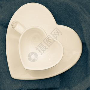 空白心脏形成咖啡或茶杯和蓝布背景的茶碟图片