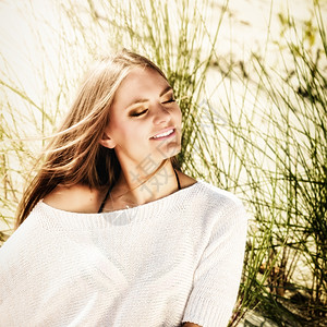 美丽的年轻女子肖像静地呼吸新鲜空气闭上眼睛坐在沙滩丘上图片