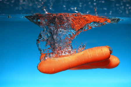 海水中的胡萝卜在蓝色背景上喷洒健康的食物和活生图片
