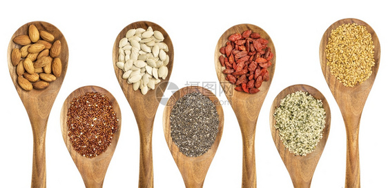 超食品抽象 -带杏仁的孤立木勺子、红quinoa谷物、南瓜种子chia果汁种子心脏和金籽图片