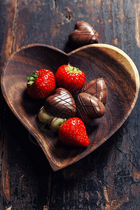 木制桌上有草莓和巧克力的心形板盘情人节和r日与爱的概念图片