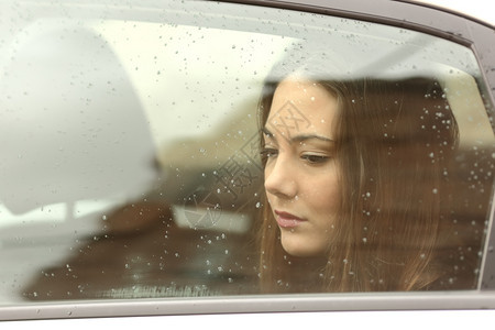 可怜的女人在雨天透过车窗向下看图片