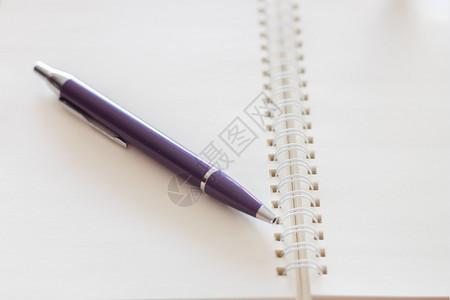 空白螺旋日记本上放着一支笔图片