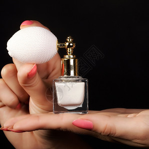感概念女用香水瓶装在黑色背景上的女手图片