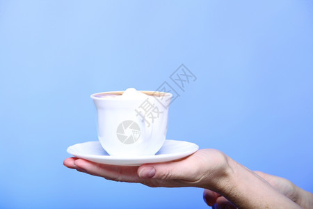 在秋冬时握着一杯拿铁咖啡卡布奇诺热饮的紧女手复制蓝色背景图片
