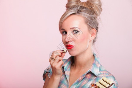 欢快的钉子女孩翻版风格肖像针女人吃巧克力粉红色背景图片