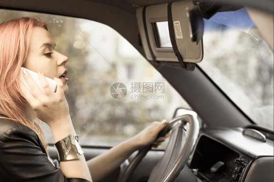 年轻女司机红发孩在开车时用手机智能电话说图片