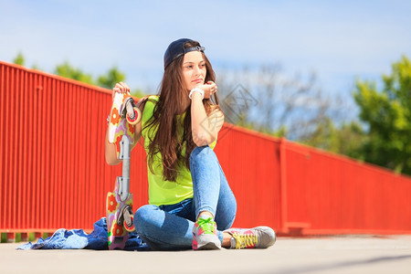酷的十几岁女孩滑冰板坐在街上外面图片