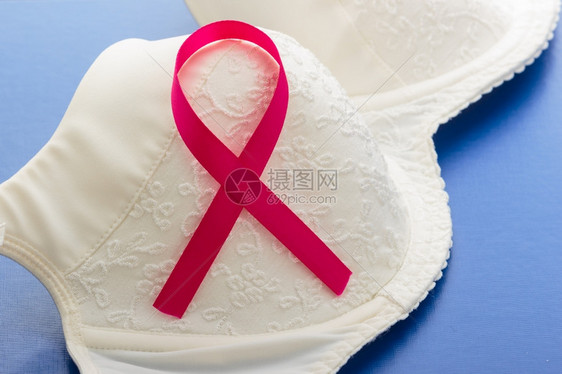 保健医药和乳腺癌认识概念蓝底女胸罩上的粉色丝带缝合图片