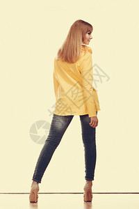 时装和人的概念穿牛仔裤长的女人高跟鞋黄色衬衫背视图片