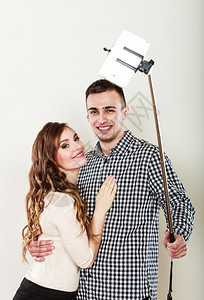 科技互联网和幸福概念年轻夫妇用智能手机相灰色背景自拍图片