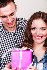 微笑的年轻男人带着礼物盒令人惊喜的快乐女图片