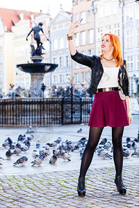 穿红发女旅行者头时装女郎拍摄自己智能手机相在欧佩安市老城格但斯克户外拍摄图片