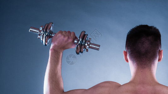 健壮体强的人与哑铃一起锻炼运动近身肌肉的年轻人举起重量后视蓝背景图片