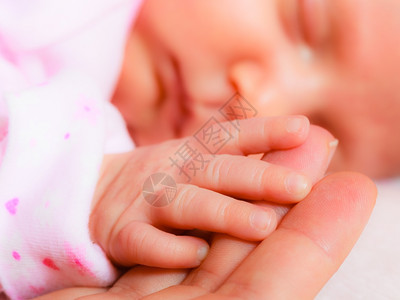 闭上小手母亲掌中睡着的女婴图片