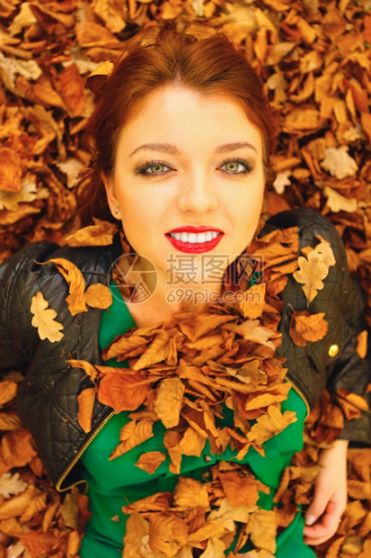 生态地球友好和爱自然概念青春的红发年轻女人躺在秋橙叶上图片