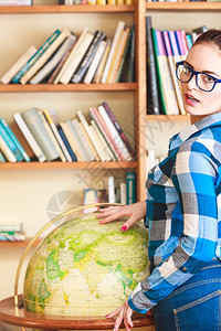 教育旅行和地理概念年轻可爱的女学生在图书馆的蓝眼镜女学生指向全球图片