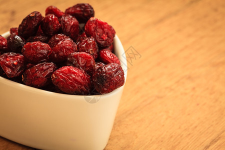 健康高纤维食品有机营养木制餐桌上的碗里闭干红莓果图片