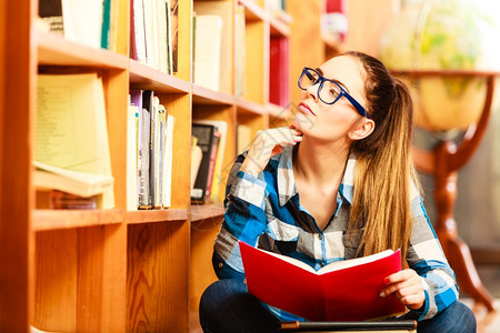 教育学校概念聪明的女学生毛发小马尾辫女孩蓝色眼镜坐在有书本的大学图馆地板上图片