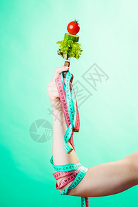 饮食和减肥概念糖尿病女手与素食和彩色的测量磁带绿色蓝背景图片