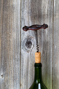 垂直图像古老的corkscrew拉出的cork在葡萄酒瓶生锈的木头上图片