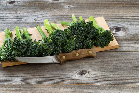 在新鲜绿色蔬菜前看见一把古老的单刀里面有生锈的木板图片