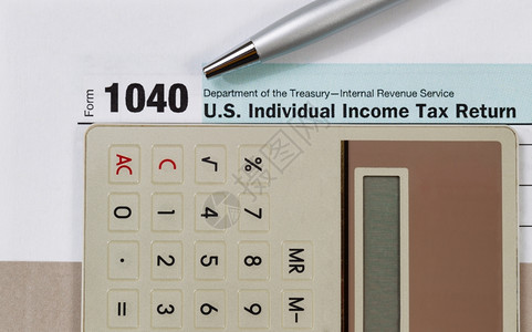 紧贴所得税表格银笔和计算器下面有灰色文件夹商业金融概念图片