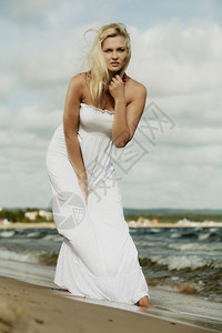 假期旅行和自由概念穿着白裙子的漂亮女孩在海滩上散步年轻女在海边放松图片