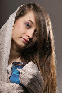 一位美丽的caucasian女人的近身拿着一杯漂亮的蓝温暖饮料灰色背景图片