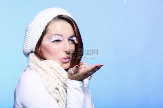 穿着温暖衣服的时装美女冬天尚的创意假扮成长的白眼鞭打吹着蓝背景的吻图片