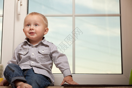 快乐的童年在家里微笑的小男孩肖像穿着蓝衬衫的可爱孩子坐在窗台上复制空间图片