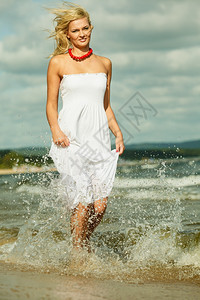 度假旅行和自由概念穿着白裙子的漂亮女孩在海滩上奔跑年轻女在海边放松愉快图片