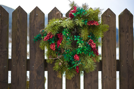 传统的圣诞花圈红莓挂在木栅栏上图片