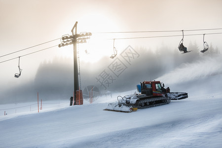 雪暴时在高滑坡上工作的撤机器侧影照片图片