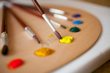 木制托盘上的多彩丙烯漆重点是用黄色涂料浸泡的油漆刷图片