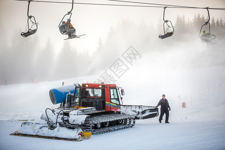 在电缆椅下滑雪坡上工作的大清洁机图片