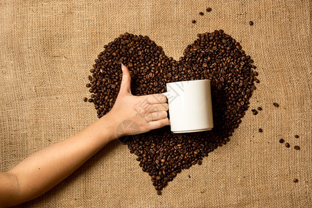 女用咖啡豆对着心脏拿杯子的照片图片