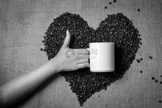 黑色和白的手相照片用拇指举起杯与咖啡豆制成的心脏对立图片