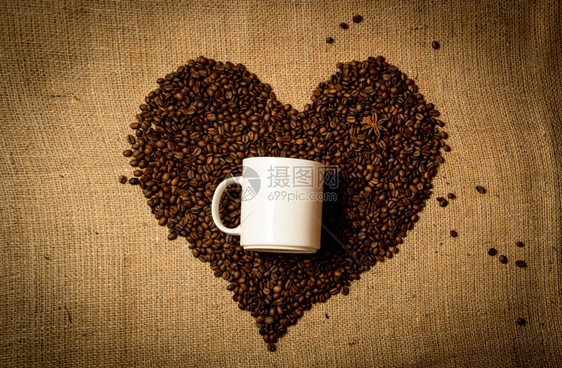 以咖啡豆制成的心脏中间白色杯子的近照图片