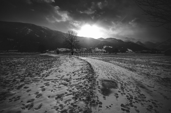 日落时阿尔卑斯山白黑雪路景色图片