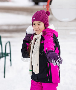 可爱女孩向摄影机扔雪球的肖像图片