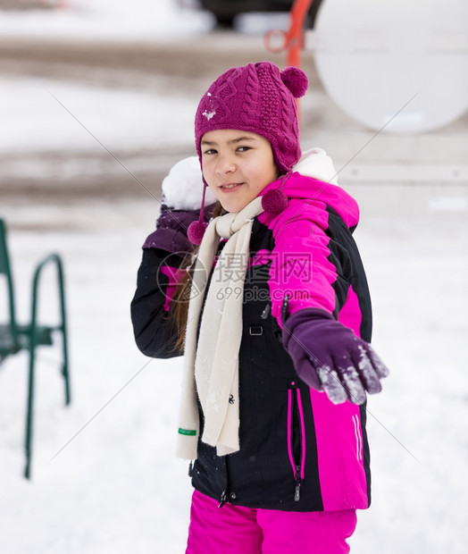 可爱女孩向摄影机扔雪球的肖像图片