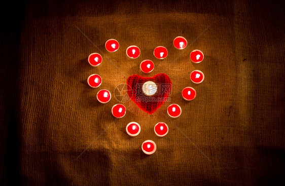 装饰的红蜡烛在麻布上形成心脏状图片