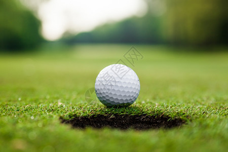 高尔夫球在绿色草地上高尔夫球在杯嘴唇上图片
