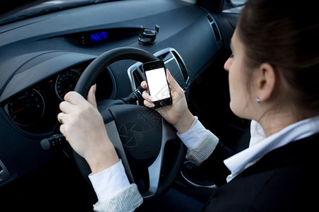 女驾驶员汽车时使用智能手机的特贴照片图片